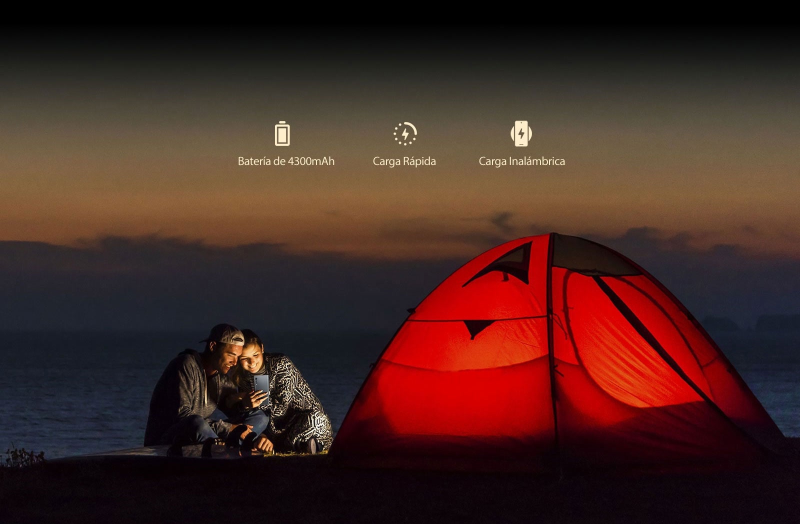 Una pareja frente a una tienda de campaña por la noche.