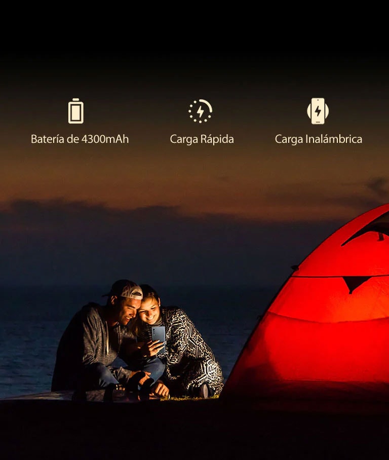 Una pareja frente a una tienda de campaña por la noche.