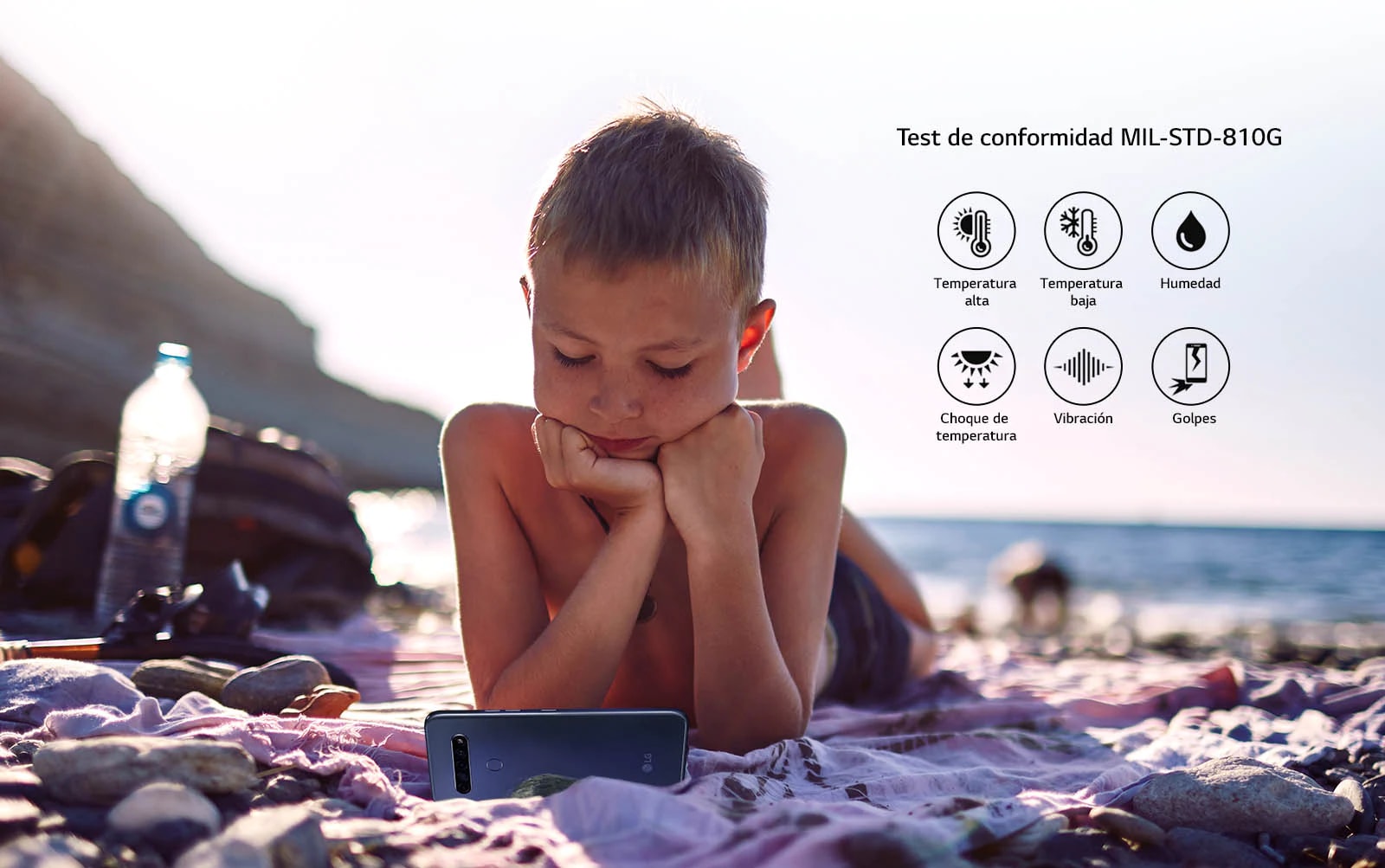 Child lying on the beach and watching a movie on his smartphone