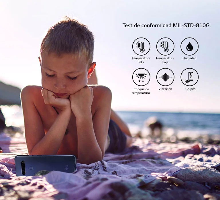 Child lying on the beach and watching a movie on his smartphone
