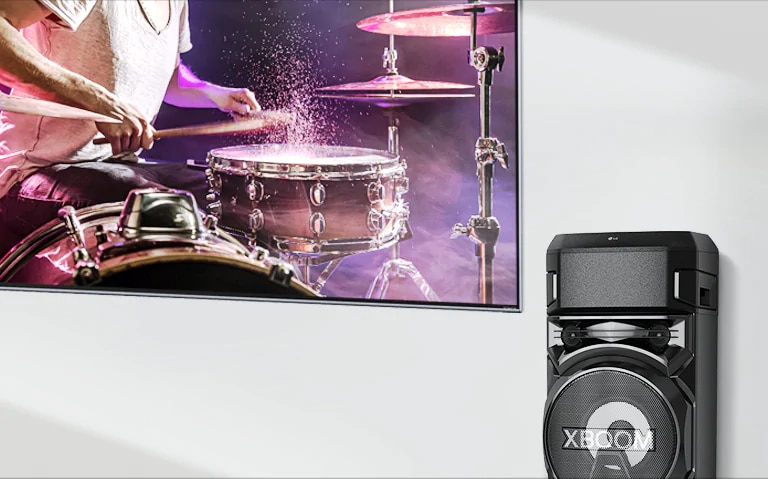 Un televisor está en una pared con un LG XBOOM a la derecha.