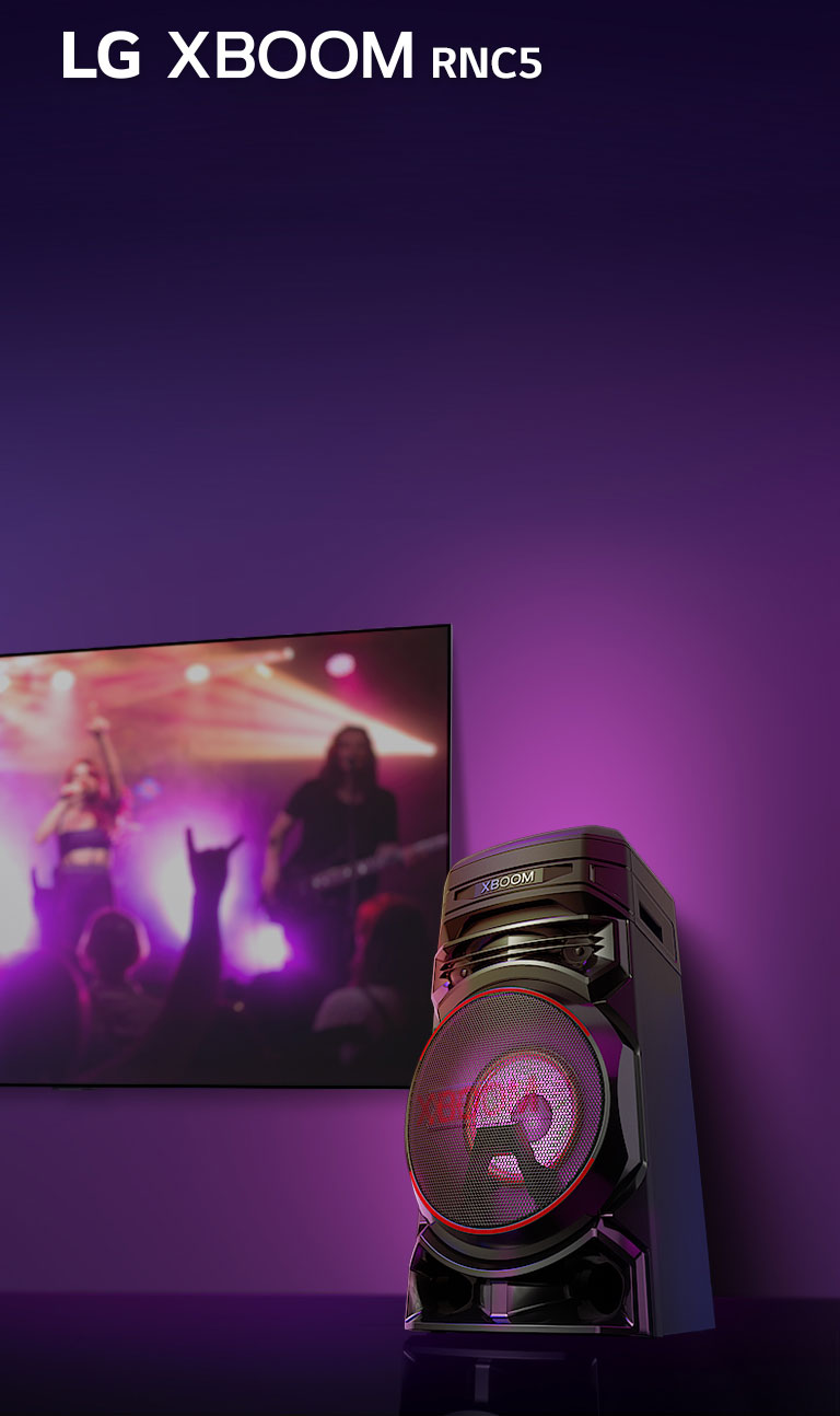 "Una vista de ángulo bajo del lado derecho del LG XBOOM RNC5 contra un fondo morado. Las luces XBOOM también son moradas. Y una pantalla de televisión muestra una escena de concierto."