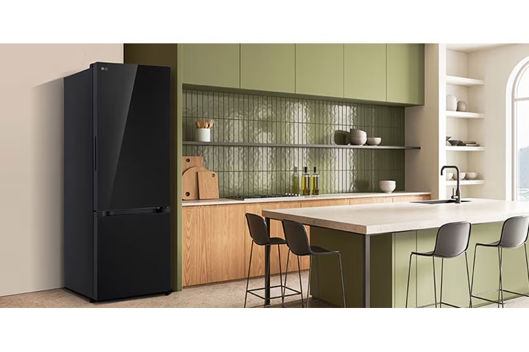 La vista lateral del refrigerador LG bottom freezer con instaview con armarios verdes y una elegante isla.