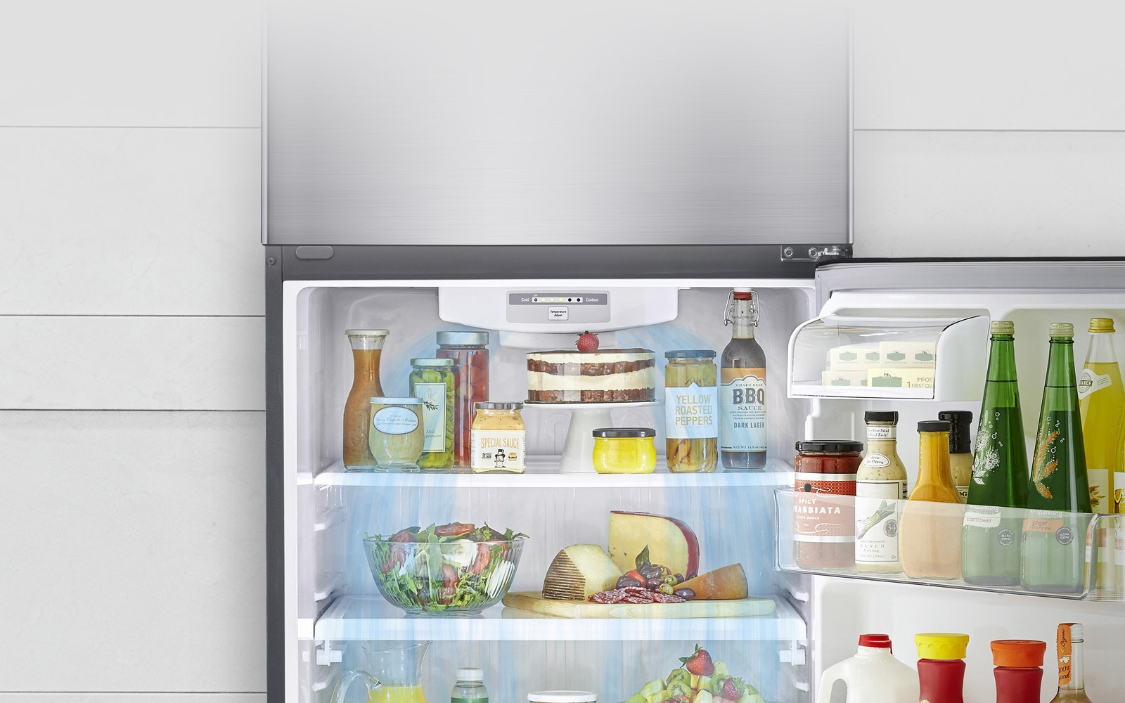 Se muestra un LG Top Freezer con la puerta inferior abierta. El refrigerador está lleno de productos y se muestra el sistema de enfriamiento liberando aire de enfriamiento que circula desde la parte superior al fondo del refrigerador.