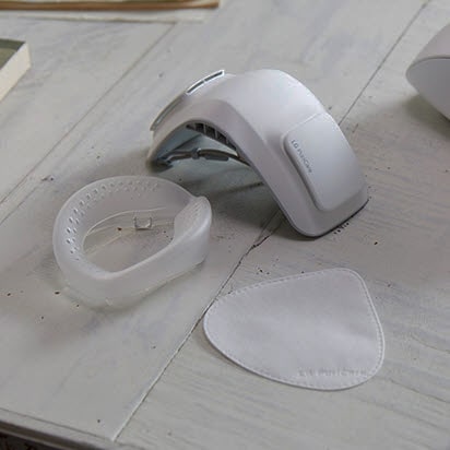 Una mano sujeta el protector de silicona y la mascarillas se muestra sobre la mesa