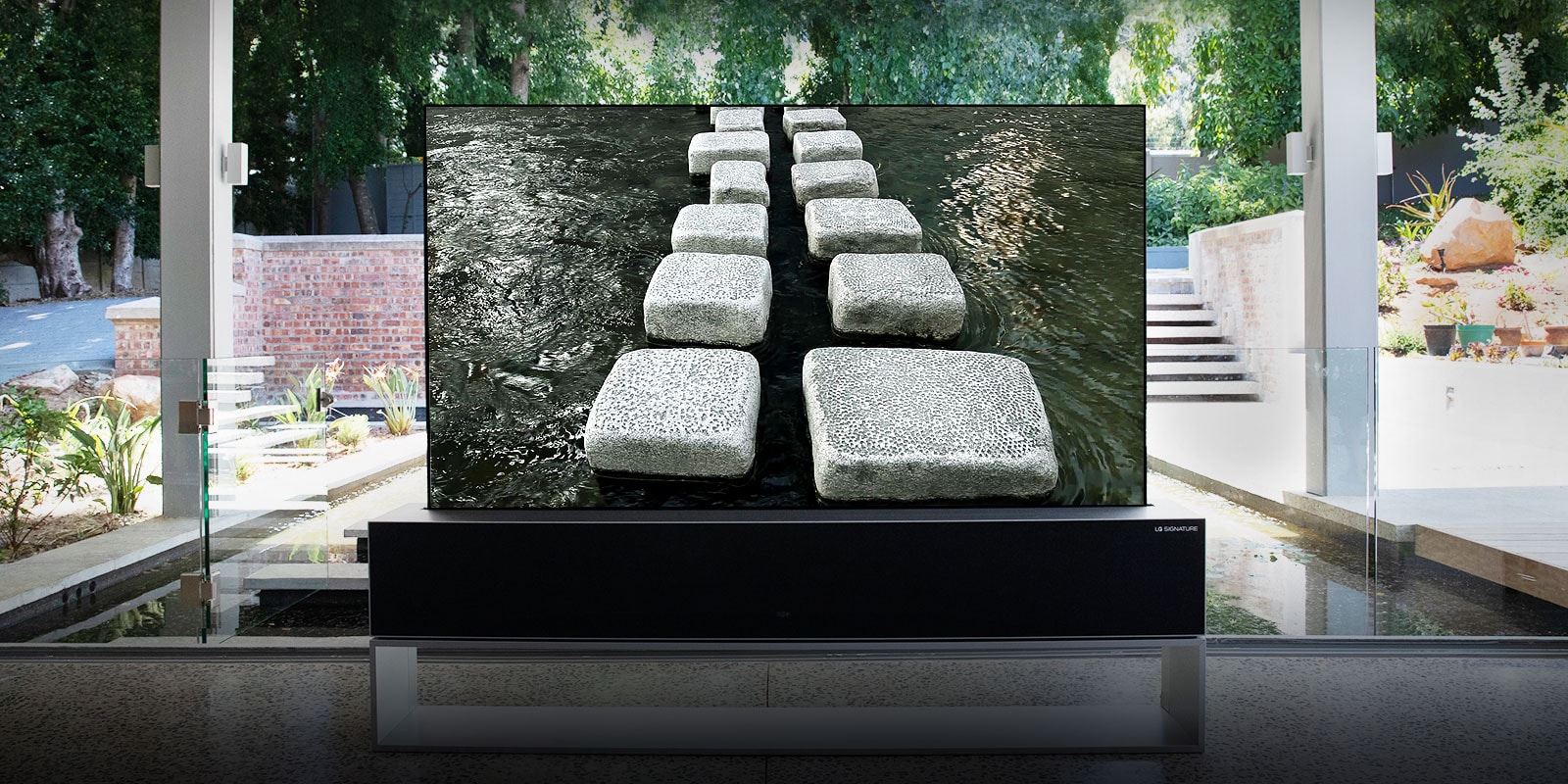 TV enrollable, frente a estanque en una casa lujosa, mostrando un puente de piedra (deslizar el sitio hacia abajo)