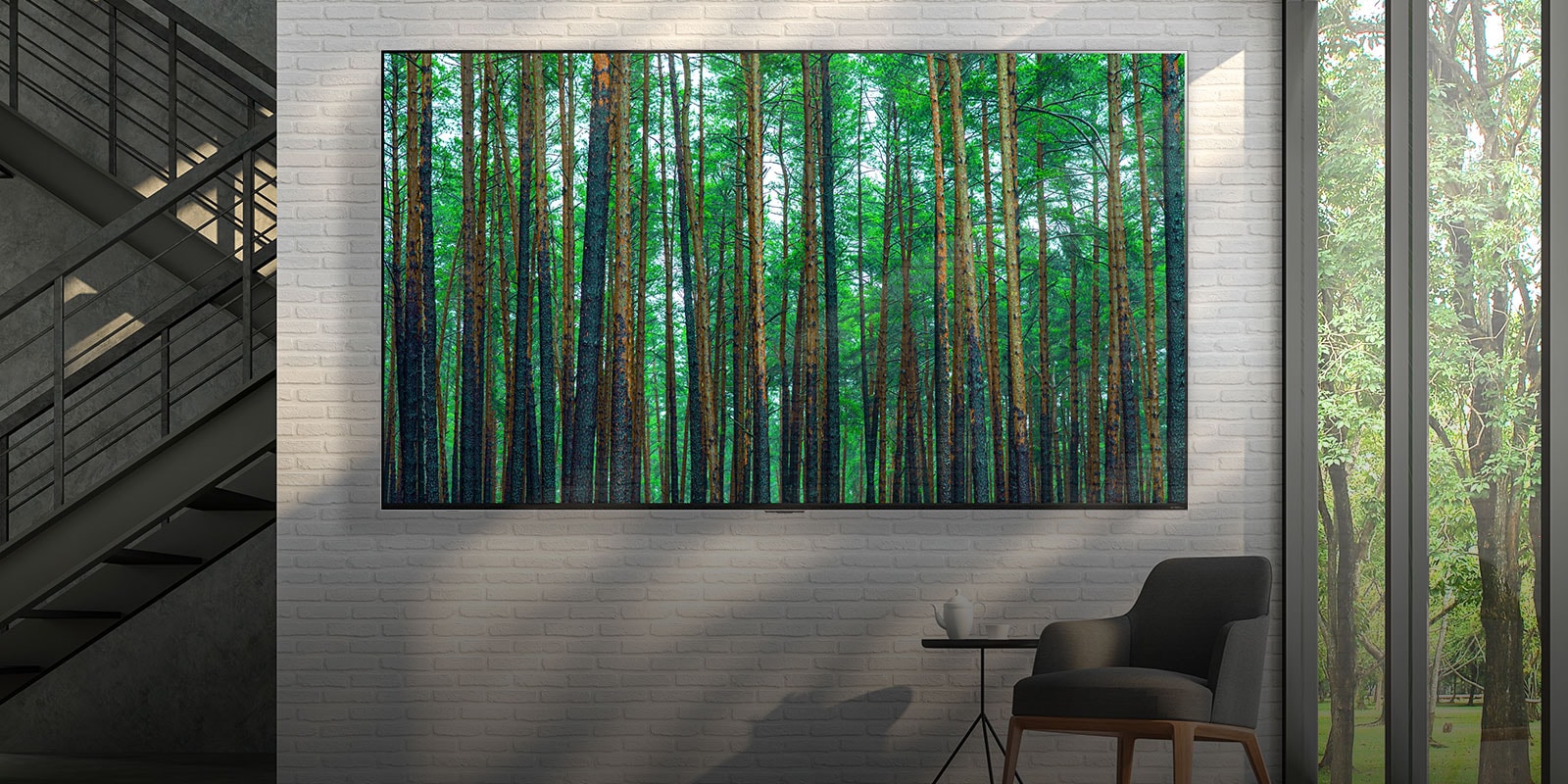 Un televisor LG QNED Mini LED de pantalla grande montada en una pared de ladrillos blanca con un pequeño sillón y una mesa en el frente. La pantalla muestra un bosque.