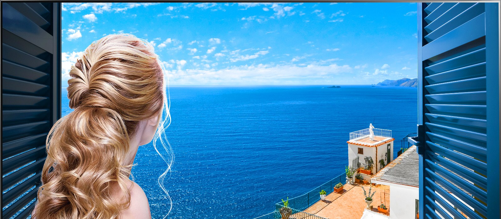 Vista trasera de una mujer mirando por la ventana un mar azul y edificaciones de color blanco. Al deslizarse en la página hacia abajo, la imagen se aleja para mostrar más de la habitación y revelar que la ventana es un televisor LG QNED Mini LED.