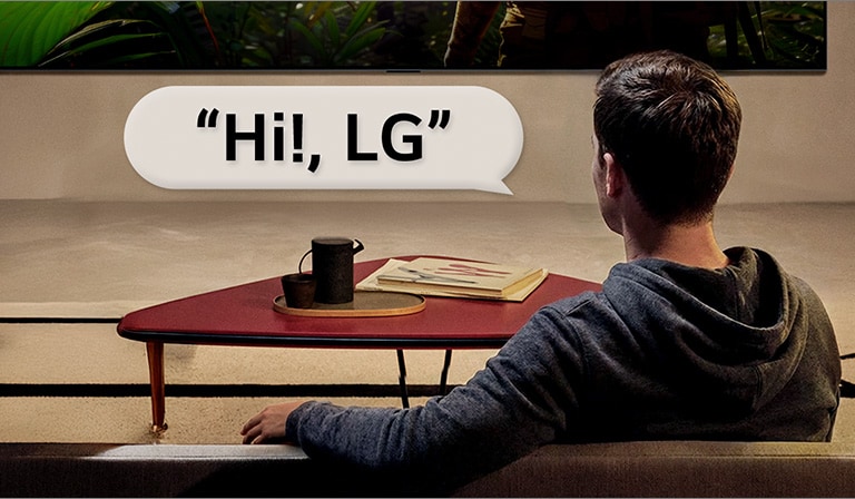 Una persona en su living. Globo de diálogo a su alrededor que muestra cómo interactúa con LG TV con solo decir: “Hola, LG”.