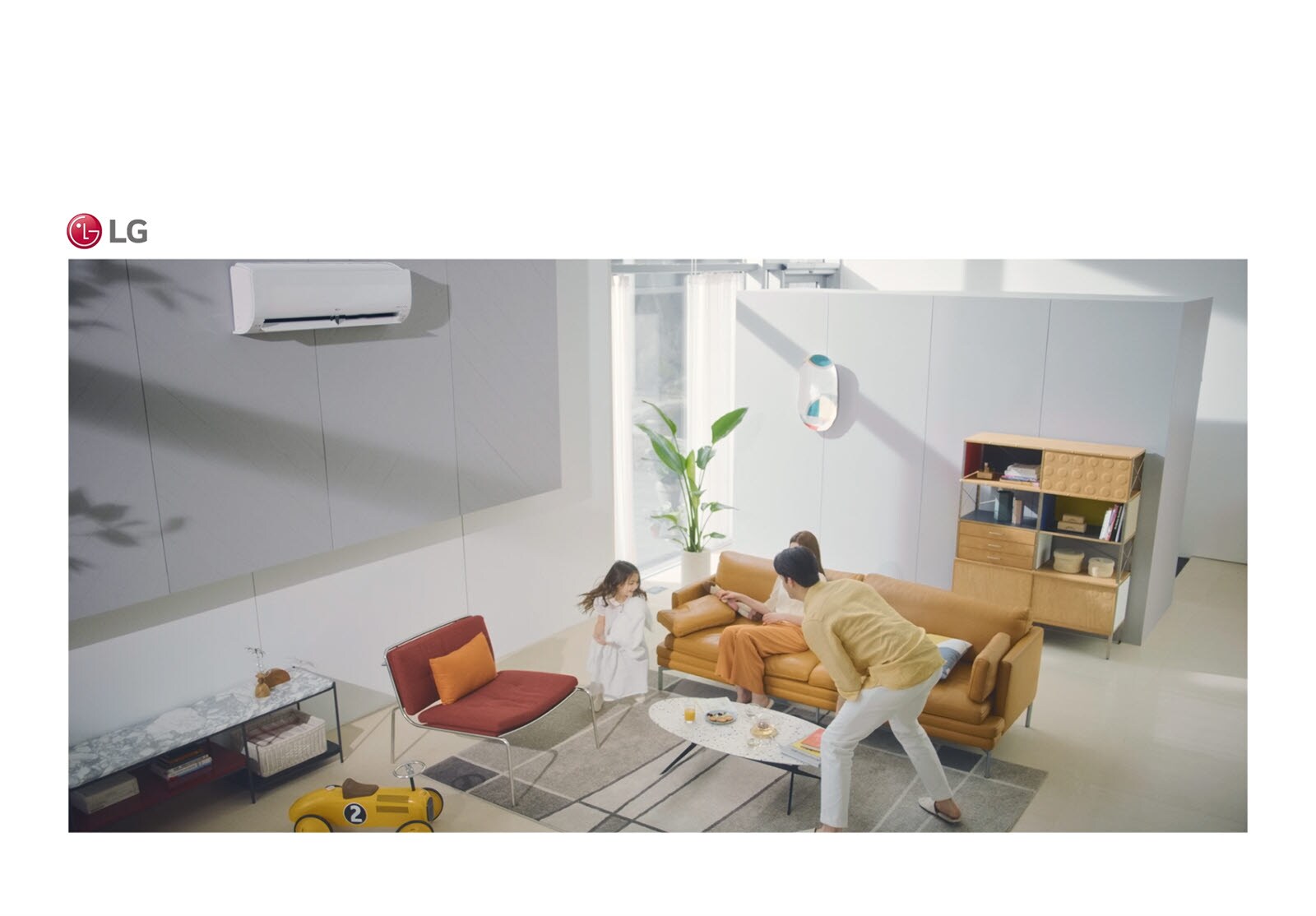 Una familia juega en una sala de estar y el aire acondicionado está en la parte superior de la imagen.