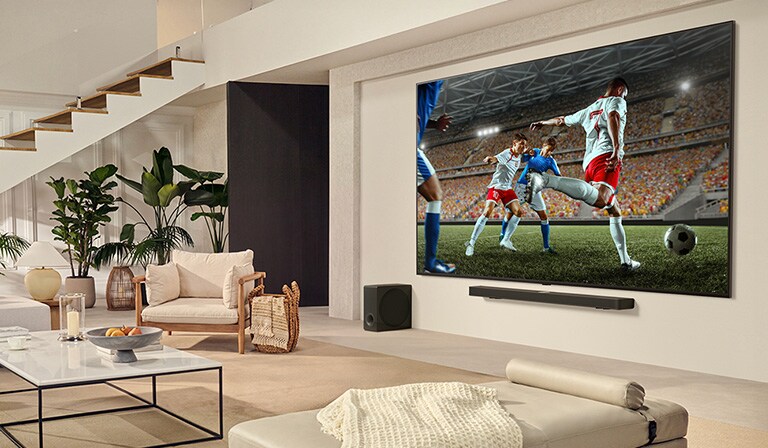 Una familia reunida alrededor de su TV ultragrande de LG viendo un emocionante partido de futbol en la enorme pantalla. 