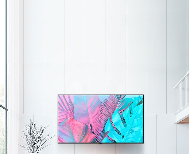 Un TV de pantalla plana grande montado en una pared de color blanco. La pantalla muestra hojas grandes en colores brillantes.