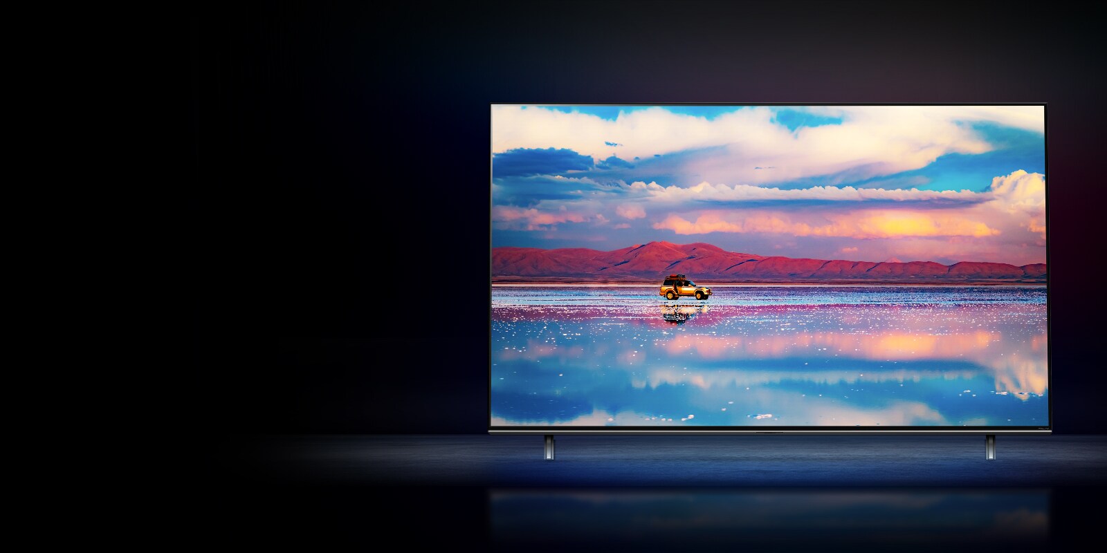 Un LG NanoCell TV en un fondo de color negro. La televisión muestra un automóvil conduciendo frente a una cadena montañosa baja en el agua que refleja el cielo intenso.