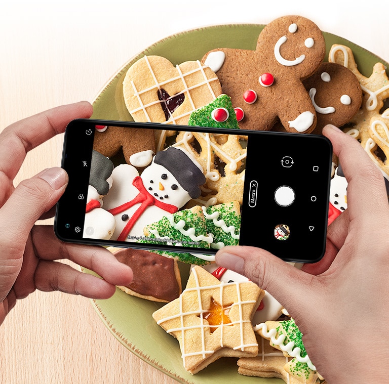 Primer plano de alguien sosteniendo un Smartphone tomando una foto de una galleta