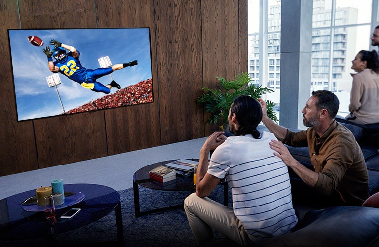 Personen, die sich ein Spiel von "Tottenham" in ihrem Wohnzimmer auf dem Fernseher ansehen