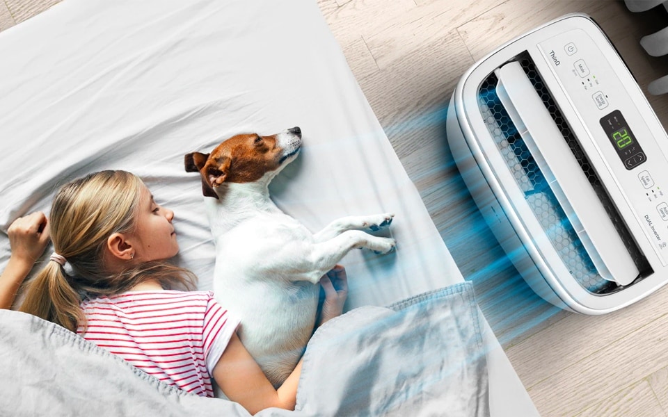 A girl and dog sleep beside a portable air conditioner.