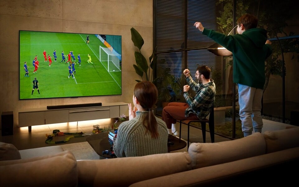Three people watch a soccer match an on OLED evo smart TV
