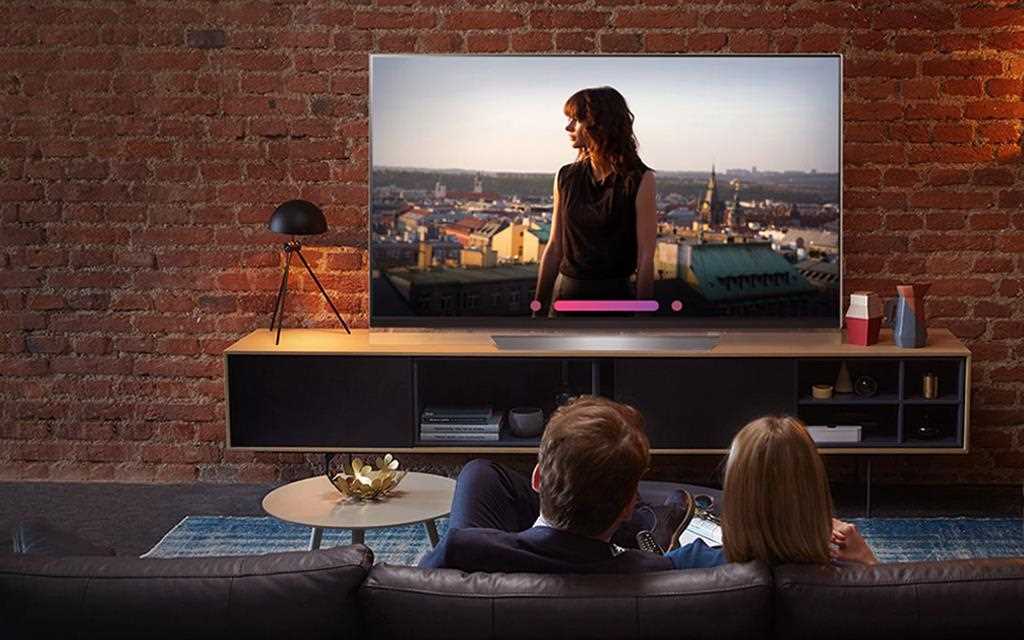 An image shows a couple watching lg super uhd tv and testing the voice command from its artificial intelligent feature. 