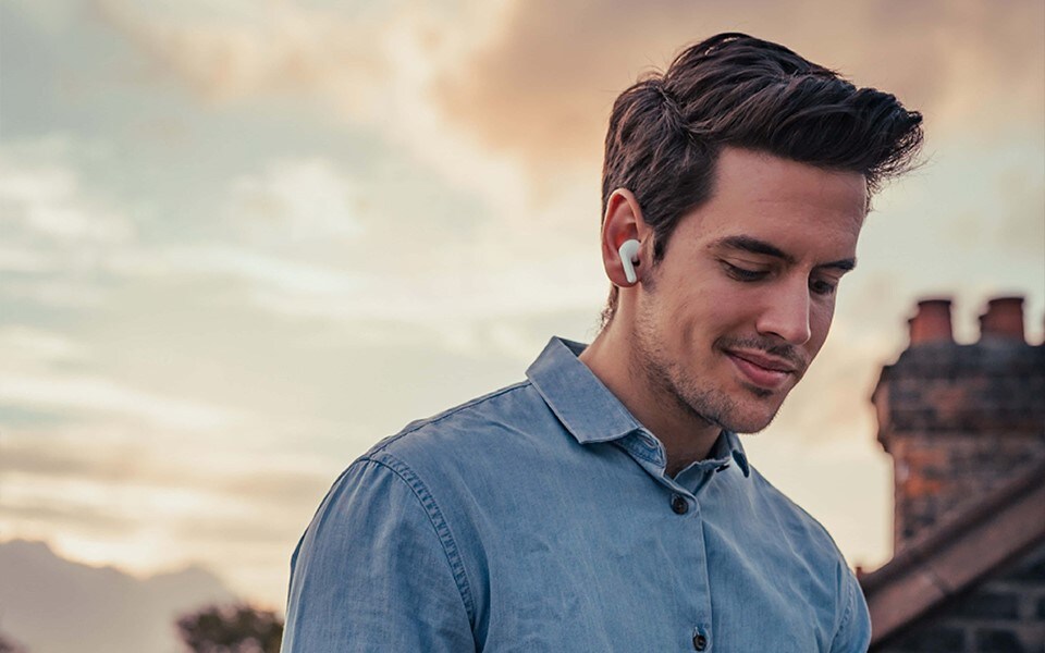 Ein junger Mann ist draußen und benutzt gesunde Ohrhörer