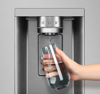 A person is getting water from the refrigerator dispenser into a glass