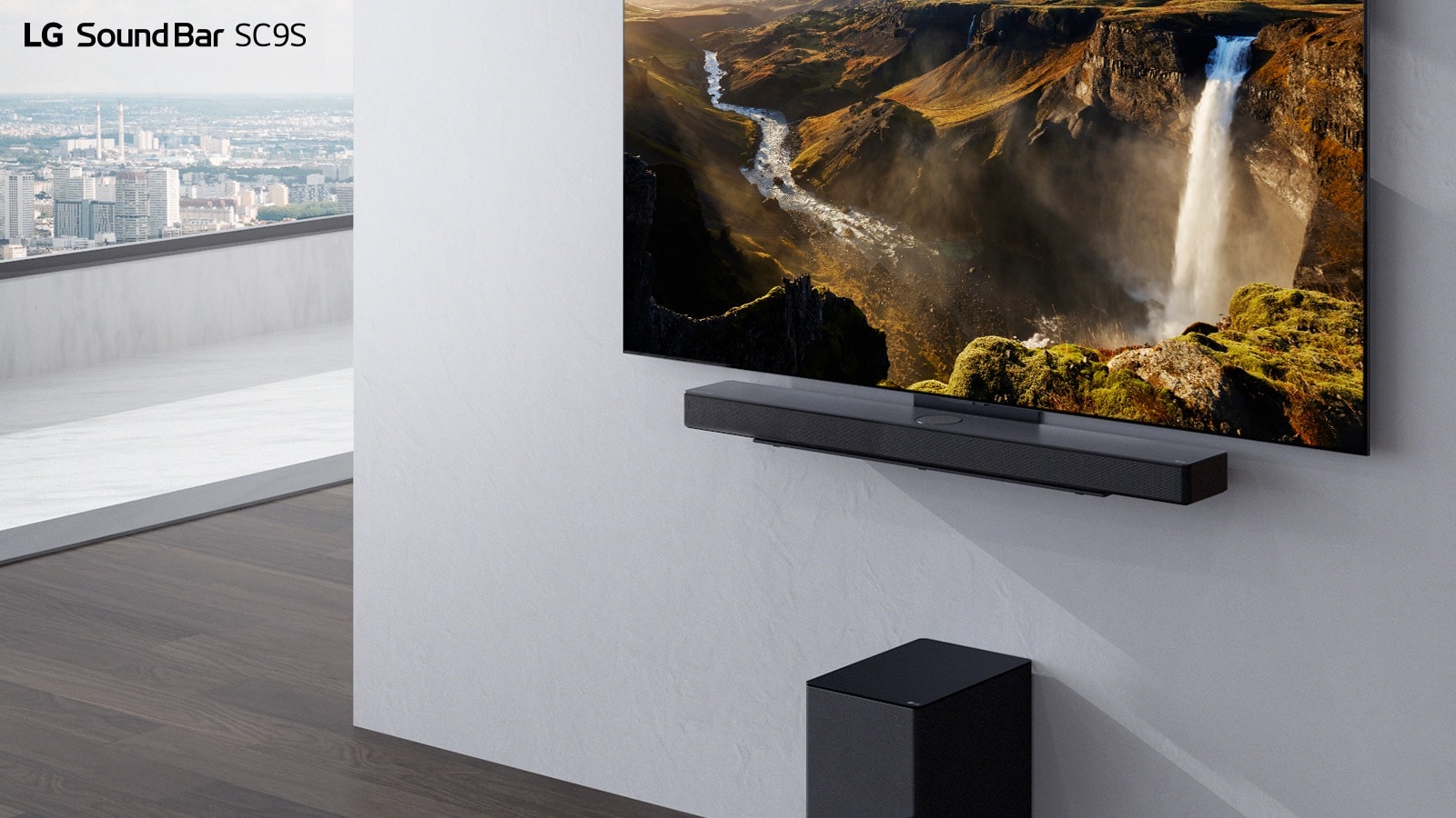 TV and LG Sound Bar SC9S are hung on a white wall. Below a black wireless subwoofer is placed on the floor. Beyond the window on the left a city view with the blue sky can be found.