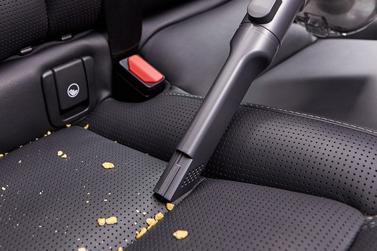 Three images: the first shows the crevice tool picking up snacks from a carseat, the second shows the brush being used on a keyboard, and the third shows the mattress tool used on a mattress.