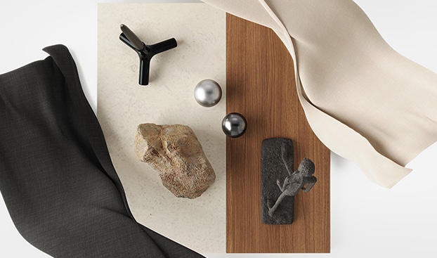 Diverse materials, such as silver ball, brown stone, and sculpture are placed on the creamy board.