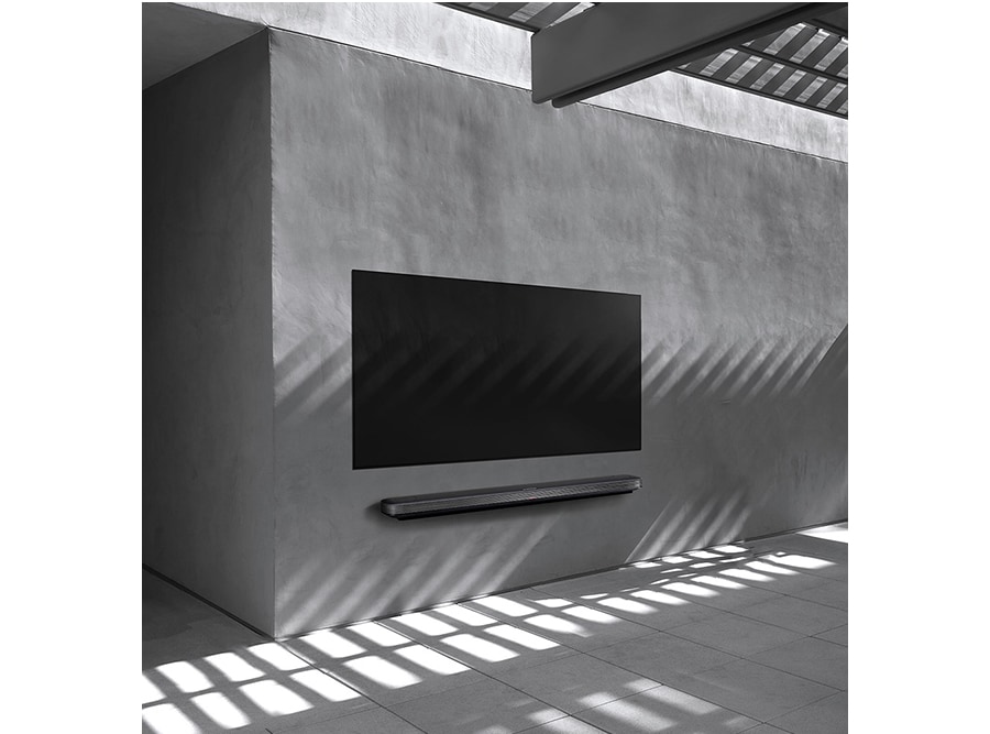 a black and white image of lg signature oled tv which is hung on the wall with some structures and shadow coming from those fabrications