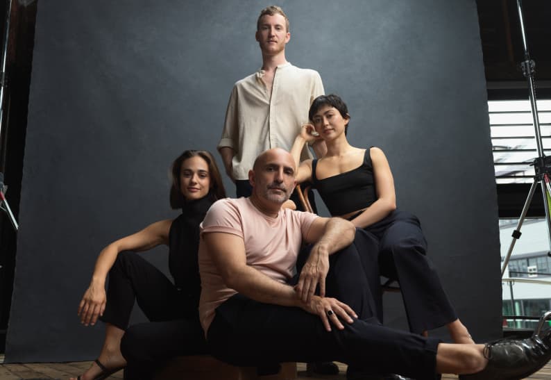 Four members of Sydney Dance Company pose together against a backdrop.