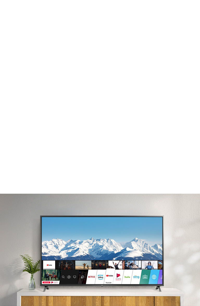 TV standing on a white stand against a white wall. TV screen shows home screen with webOS.