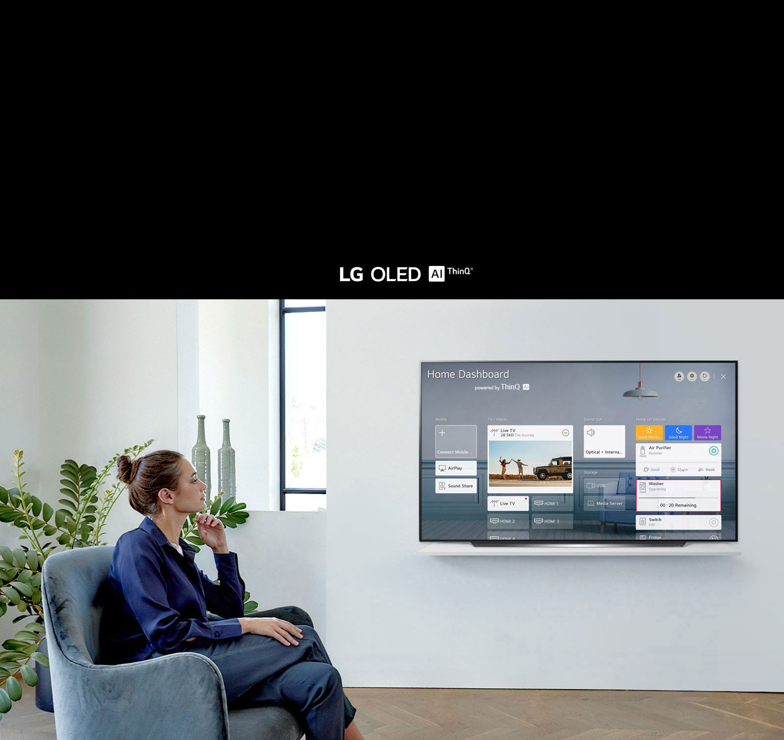 Woman sitting on a chair in the living room with the Home Dashboard on the TV screen