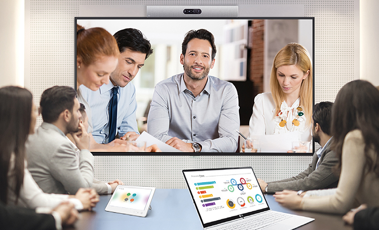 A video conference is being held as people are  screened on signage installed on the wall. 
