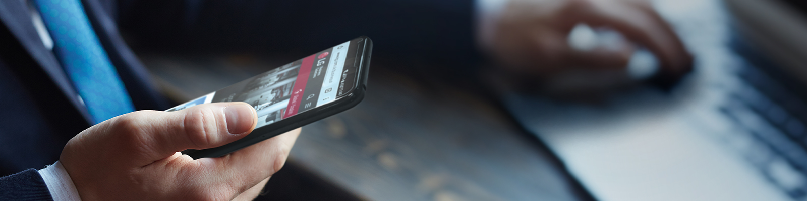 An image of a man holding a smartphone with LG web page on the screen.