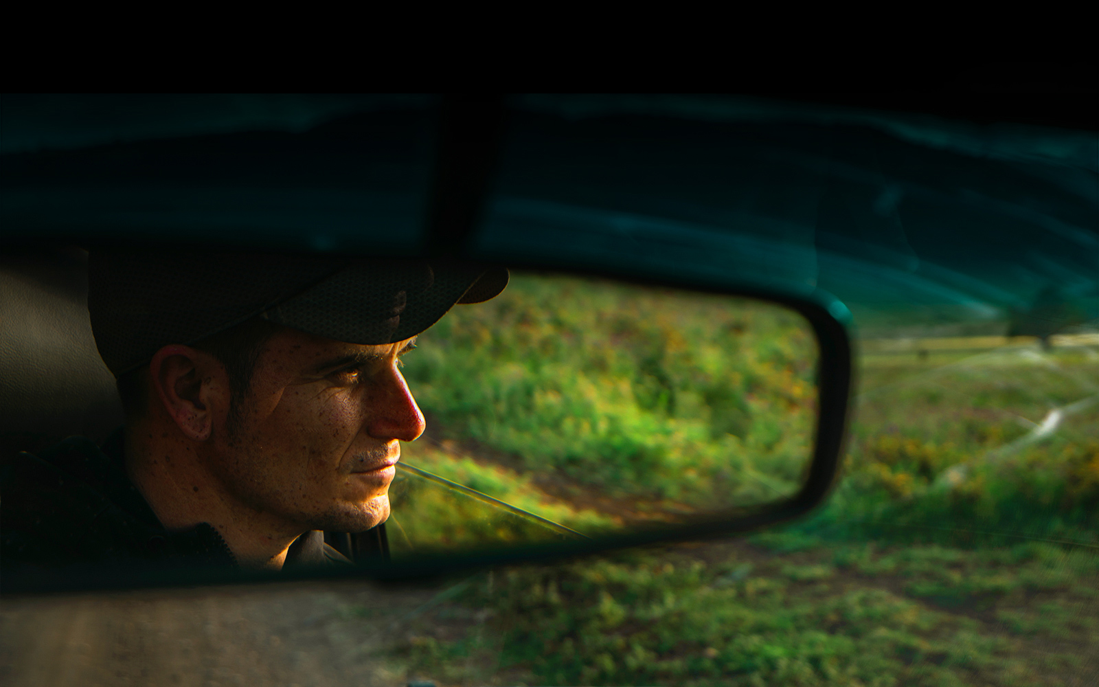Reflection of man in car rear view mirror. Scene zooms out to show the same scene in QNED TV.