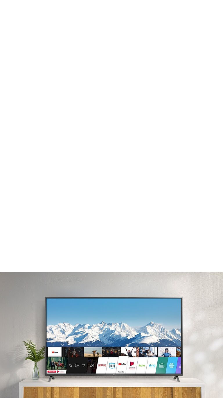 TV standing on a white stand against a white wall. TV screen shows home screen with webOS.