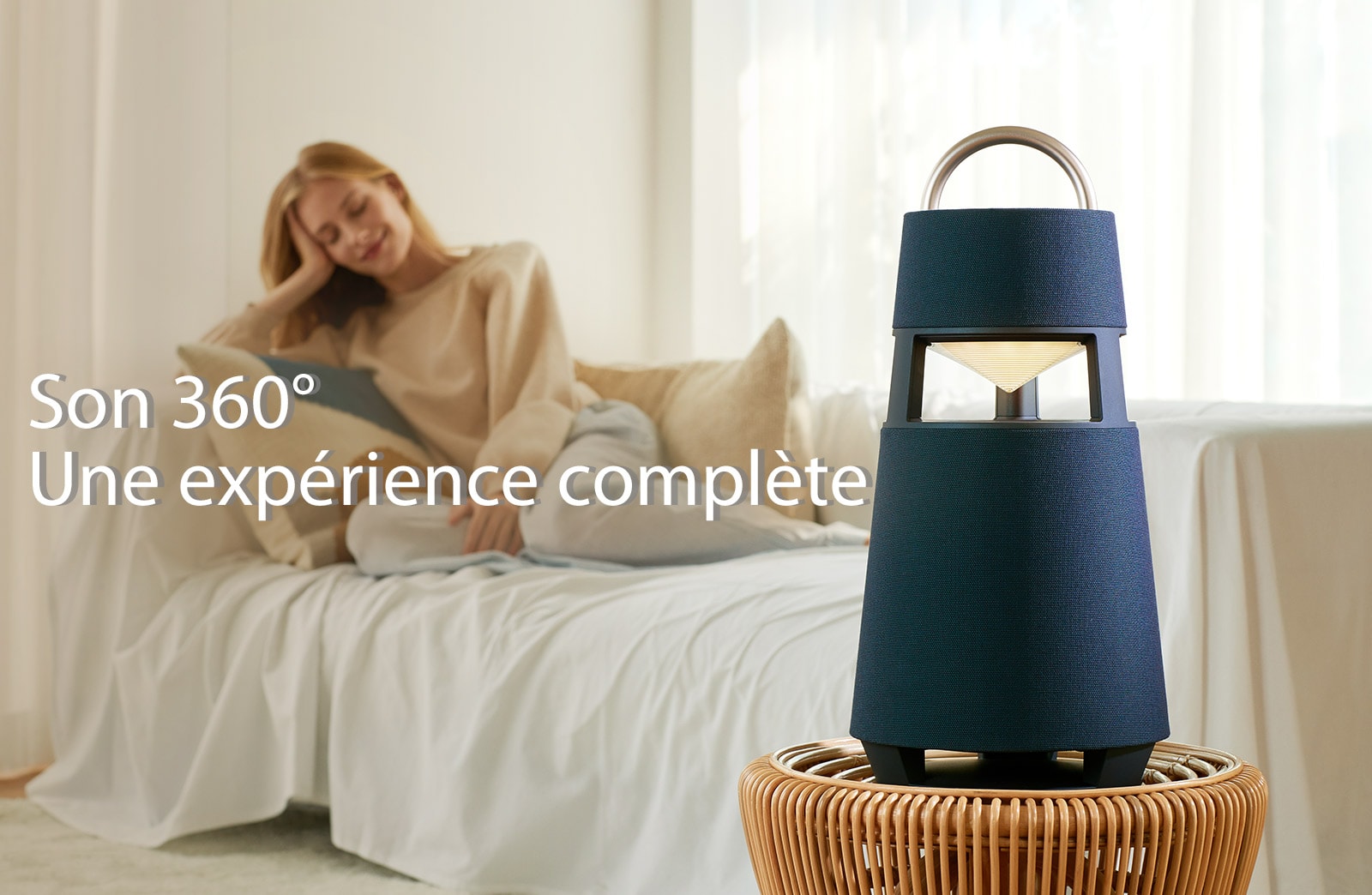 Image d’une femme assise sur un canapé écoutant de la musique grâce à une enceinte XBOOM 360 posée devant elle.