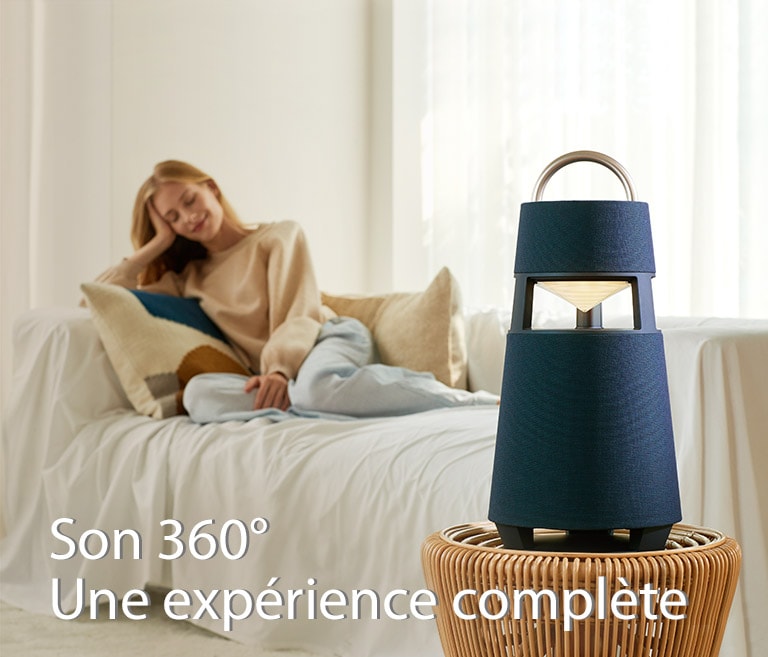Image d’une femme assise sur un canapé écoutant de la musique grâce à une enceinte XBOOM 360 posée devant elle.