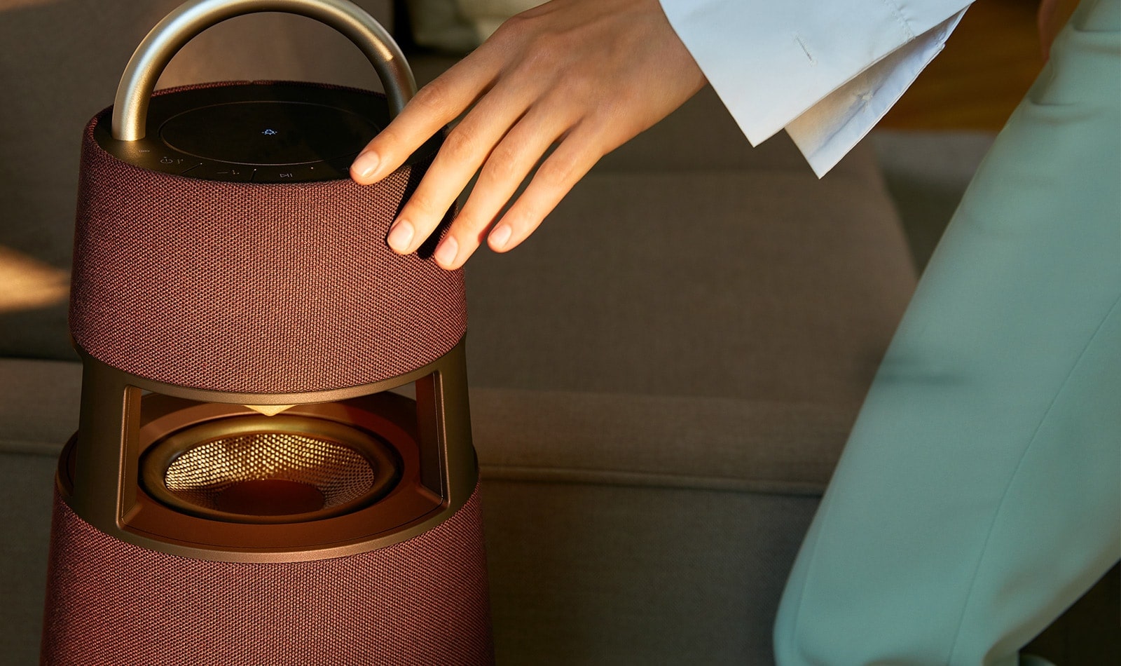 Image d’une femme touchant l’extérieur d’une enceinte XBOOM 360 de couleur bordeaux.