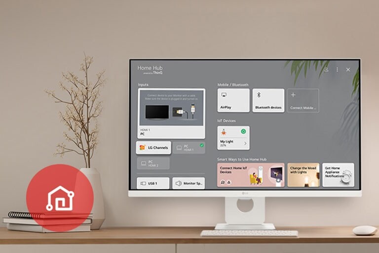 Sur la table, le moniteur affiche l’écran Accueil et l’icône de l’appli LG ThinQ est visible dans le coin inférieur gauche.