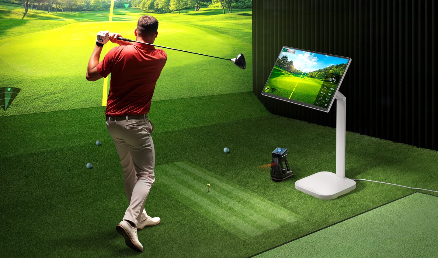 Un homme joue au golf dans une installation de golf à écran intérieur, avec un LG Smart Monitor Swing à côté de lui affichant des données.
