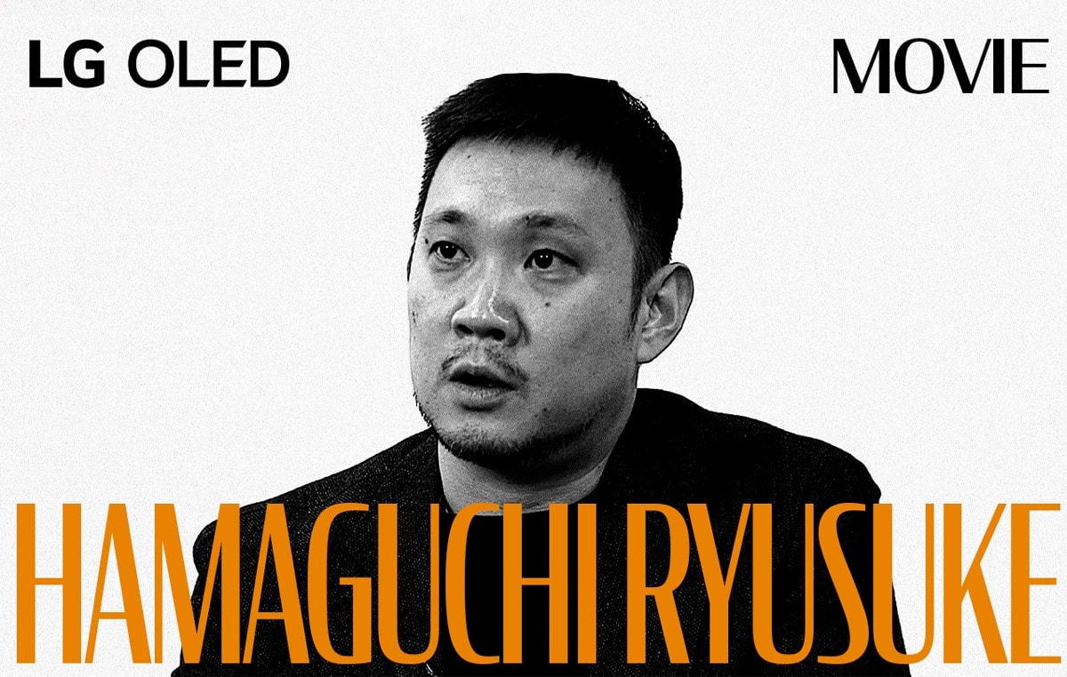 Une image en noir et blanc provenant de l’entretien avec Hamaguchi Ryusuke. Son nom apparaît en lettres majuscules orange sur le bas de l’écran. LG OLED apparaît dans le coin supérieur gauche et le mot « film » est visible dans le coin supérieur droit. 