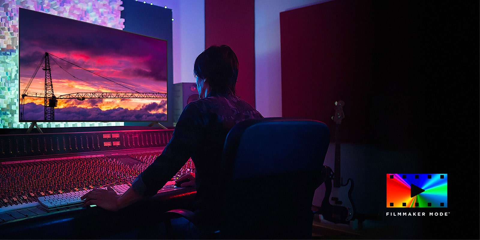 Un homme dans un studio de montage sombre regardant un LG TV affichant le coucher du soleil. En bas à droite de l’image se trouve le logo du FILMMAKER Mode.