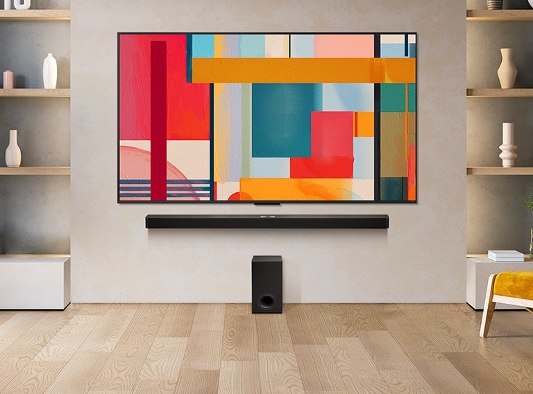 LG QNED TV fixée sur un mur au-dessus d’une LG Soundbar dans un salon moderne. La LG QNED TV représente un arrière-plan abstrait en vert, rouge et orange.