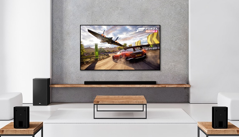 Un ensemble de 2&nbsp;haut-parleurs arrière, un caisson de basses, une barre de son et un téléviseur se trouvent dans un salon blanc. On peut voir une voiture qui roule et un vaisseau spatial sur l’écran du téléviseur.
