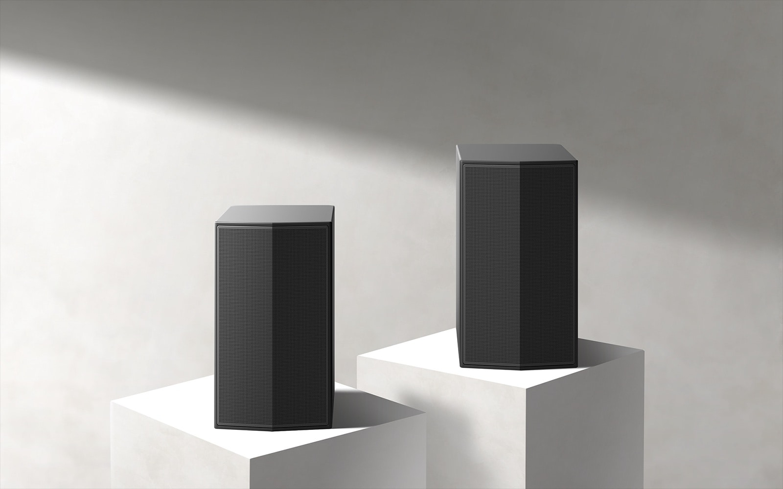 Les enceintes arrières sur un podium en marbre dans un espace blanc. 