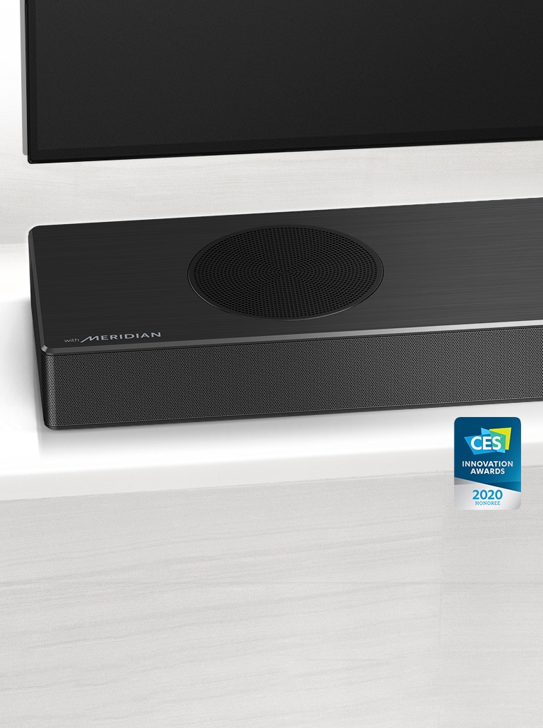 Gros plan de la barre de son LG sur le côté gauche, avec le logo Meridian en bas à gauche. Le côté inférieur gauche du téléviseur est également visible. 