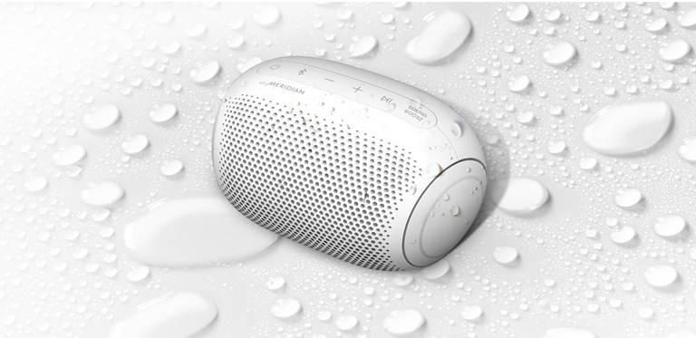 Sur un fond blanc, le LG XBOOM Go est orienté vers la gauche. Il y a des gouttelettes d’eau sur le LG XBOOM Go et en dessous de celui-ci.