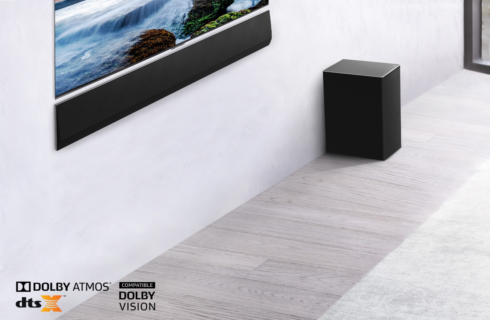 Le téléviseur et la barre de son LG sont fixés au mur avec un caisson de graves en dessous et à droite. Le téléviseur présente un coucher de soleil en mer.