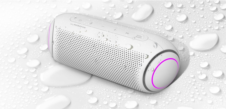 Sur un fond blanc, le LG XBOOM Go est orienté vers la gauche. Il y a des gouttelettes d’eau sur le LG XBOOM Go et en dessous de celui-ci.