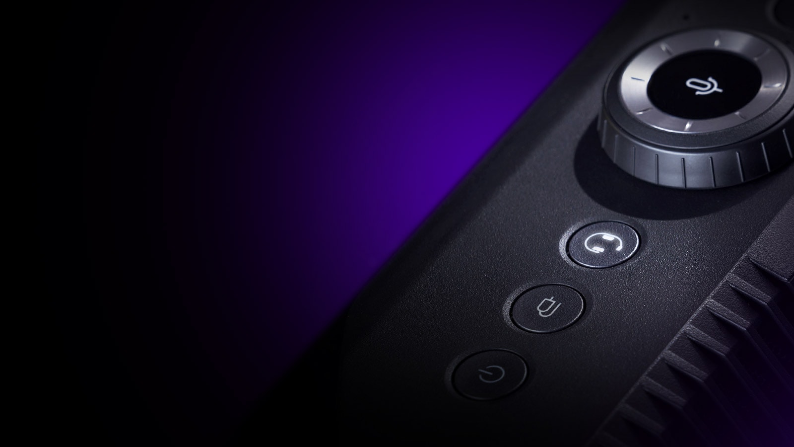 Une vue en diagonale du haut-parleur de jeu depuis la partie supérieure, mettant en évidence le bouton du casque d’écoute sur sa partie supérieure et un effet d’éclairage violet visible à l’arrière.